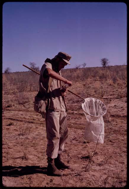 Wulf Haacke standing, holding a collecting net, putting a lid on a jar