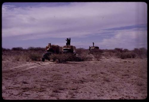 Expedition members standing on or near trucks stopped on a road