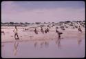 People sitting and standing at the edge of a pan filled with water