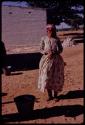 Woman standing, with a building in the background