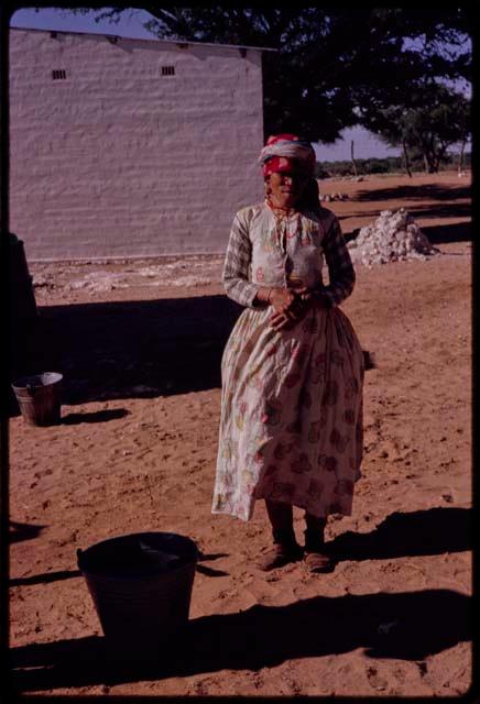 Woman standing, with a building in the background