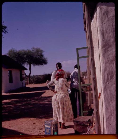 Woman standing with two men next to the door of a building, view from behind