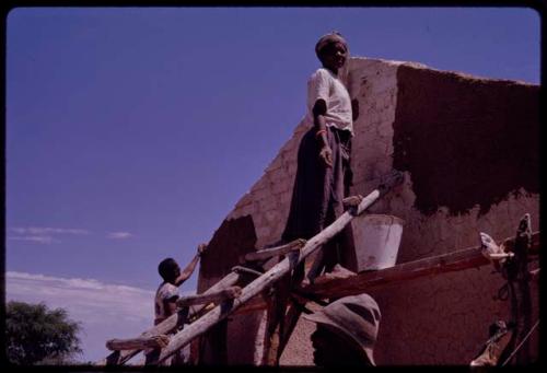 Woman plastering the exterior wall of a new house with mud and dung, in the compound of Boy Moapane, brother of the Kgalagari chief