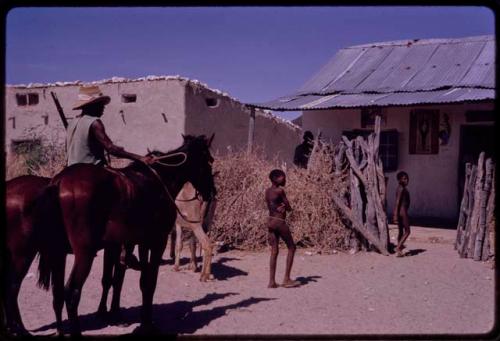 Man with horses, children standing, in front of Rasool's store