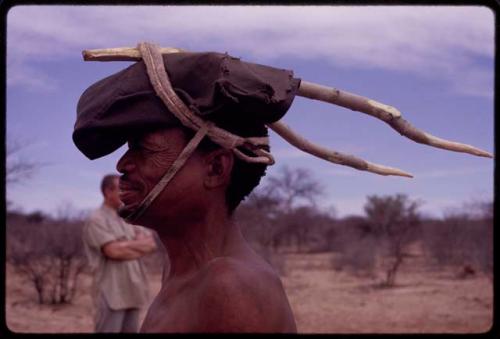 !Kxam wearing eland horns for the Eland Dance, made from twisted sticks, tied on with thongs, profile