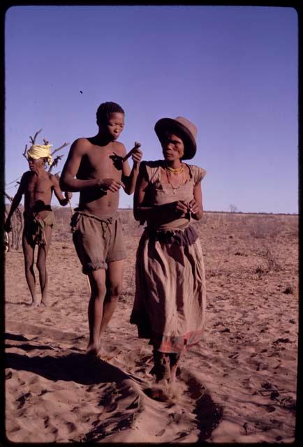 Dadum performing a social dance with her husband, Tama, with /Xoxa wearing a kerchief on his head in the background