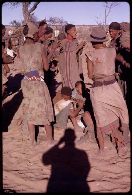 Group of people, including Tomku and Dadum, performing a social dance, view from behind