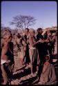 Group of people performing a social dance around a group of women clapping