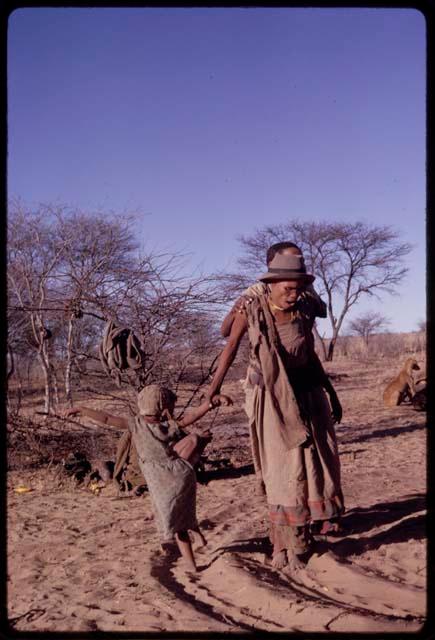 Dadum performing a social dance, holding N//aba's daughter by the hand