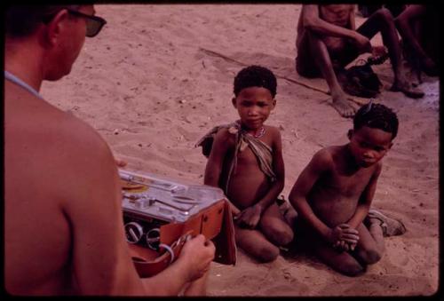 Children sitting, listening to a sound recording of a dance being played by Nicholas England