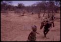 Child running next to a man wearing horns at the Eland Dance