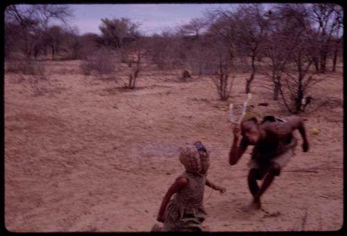 Child running next to a man wearing horns at the Eland Dance