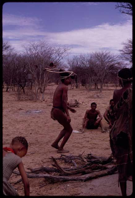 !Kxam wearing horns tied to his head, dancing in the Eland Dance, distant view