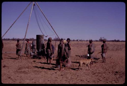 Group of people waiting for water to be poured at a borehole