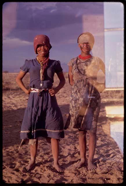 Two girls with face paint, wearing dresses and standing