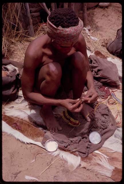 Dadum squatting and doing beadwork