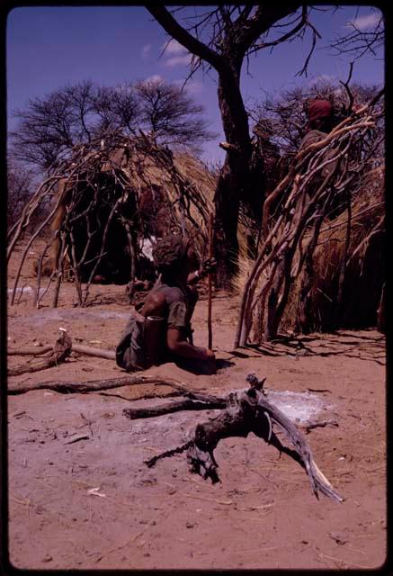 Woman digging a hole with her digging stick in which to stand one of the supporting branches of a skerm