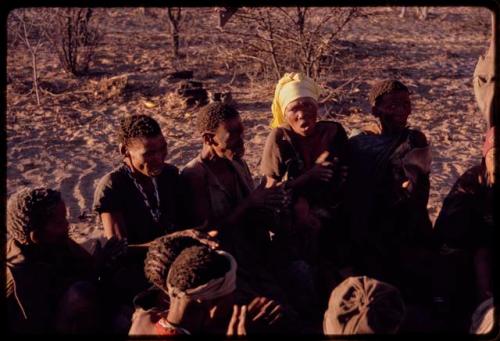 Group of women, including N/aoku, Tomku, and N≠isa?, sitting in a circle and clapping to a curing dance