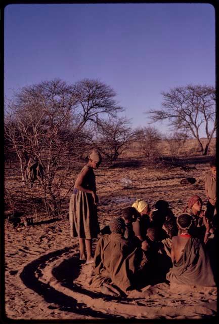 Tomku taking her place in a group of women sitting in a circle for a curing dance