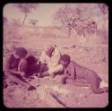 Expedition: Gau fixing Laurence Marshall's shoe by making a hole with an awl and sticking thread through the hole, with "Gao Medicine" sitting with them