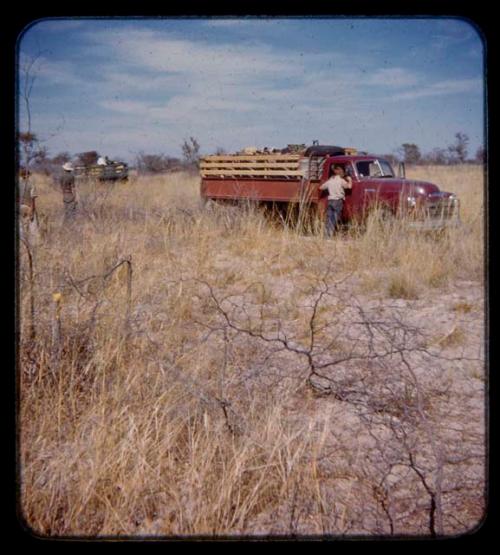 Person standing at an expedition truck's window, seen from behind