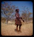 Man holding objects and standing on the road between Chitado and Oncocua