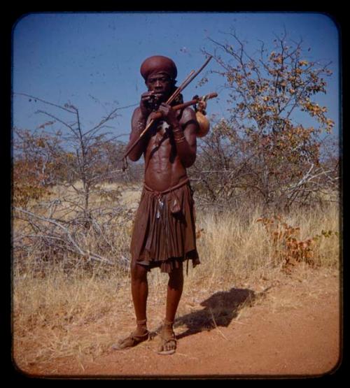 Man holding objects and standing on the road between Chitado and Oncocua
