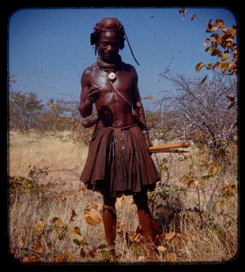 Man holding objects and standing on the road between Chitado and Oncocua