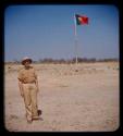 Alberto Eugenio de Moraes (Chief of Post Chitado) standing, with the flag of Portugal in the background