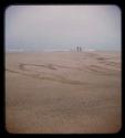 Sand and sea, with two people standing from a distance