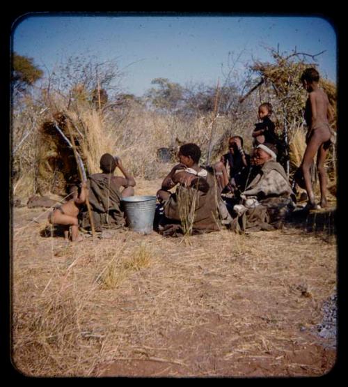 Group of people sitting, with a bucket in the center