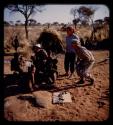 Group of boys playing with plasticene models, with Lorna Marshall, Elizabeth Marshall Thomas, and John Marshall watching them