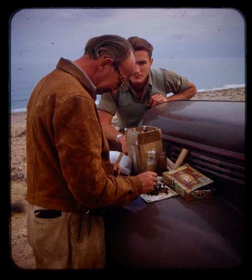 Charles Koch examining a beetle, with Heiner Kretzchmar watching him