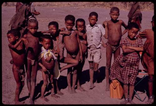 Group of children; Norna, in the plaid dress; to her left in red and white stringed dress is //Kushay, wife of Tsamgao; ǂToma's son; daughter of /Qui and /Gasa; behind Norna is /Qui, son of Gau and Khan//a; and the boy in white suit is ǂToma's son, /Gaishay; and other children