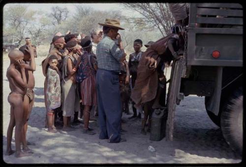 Group assembling, preparing to get into an expedition truck for a mangetti gathering trip, close-up