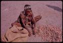 Woman sitting by pile of mangetti nuts, close-up