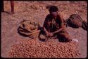 Woman sitting, beginning to pack up her nuts