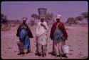 Three women walking to a waterhole with metal buckets