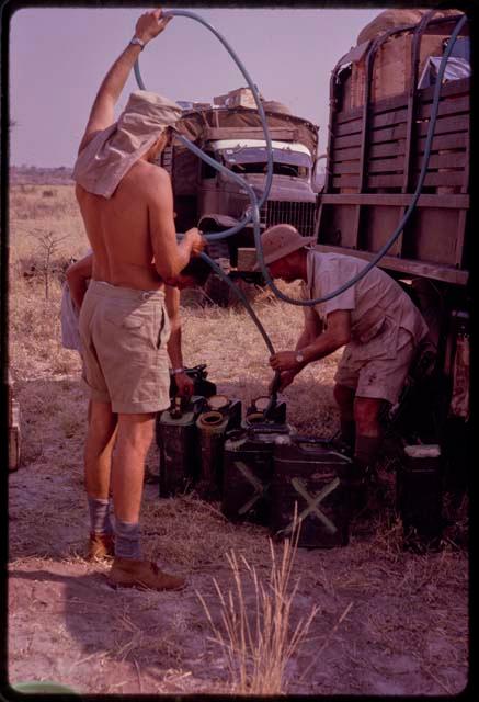 Expedition members filling cans with water from an expedition truck water drum