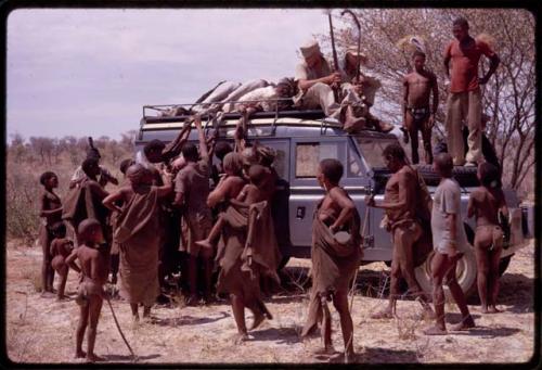 Group of people gathered around an expedition Land Rover, O.P.M. Prozesky and Wulf Haacke sitting with a dead ostrich on top of the Land Rover