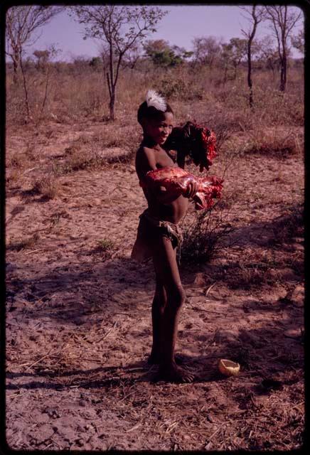 Boy carrying his family's share of meat to their skerm