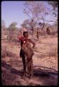 Woman carrying her share of ostrich meat, people in the background carrying meat