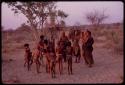 Adults gathering for a curing dance, women clapping and children dancing