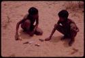 Two boys making toy cars out of a root