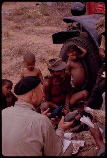 Group of people sitting with O.P.M. Prozesky, Nicholas England, Dabe, and Lorna Marshall and identifying birds; O.P.M. Prozesky holding birds, close-up