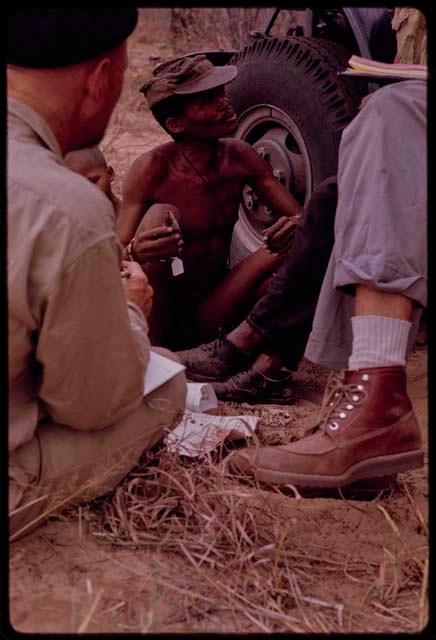 Group of people sitting with O.P.M. Prozesky, Nicholas England, Dabe, and Lorna Marshall and identifying birds; a man holding a bird, close-up