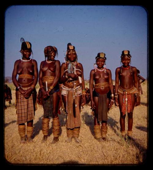 Five women standing in a row wearing headdresses