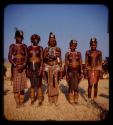 Five women standing in a row wearing headdresses