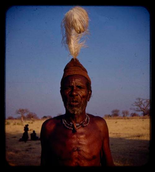 Elderly man wearing a hat with a white feather, close-up