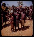 Group of people standing by a road, young girls standing in front